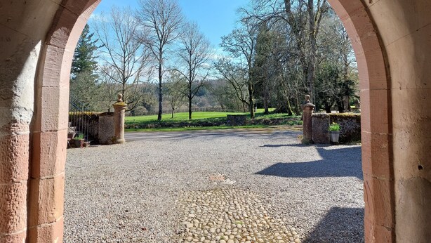An arched entrance with a gravel path leading to a green park area. - Aigas holiday cottages Pond View (By Beauly,, Inverness-shire)