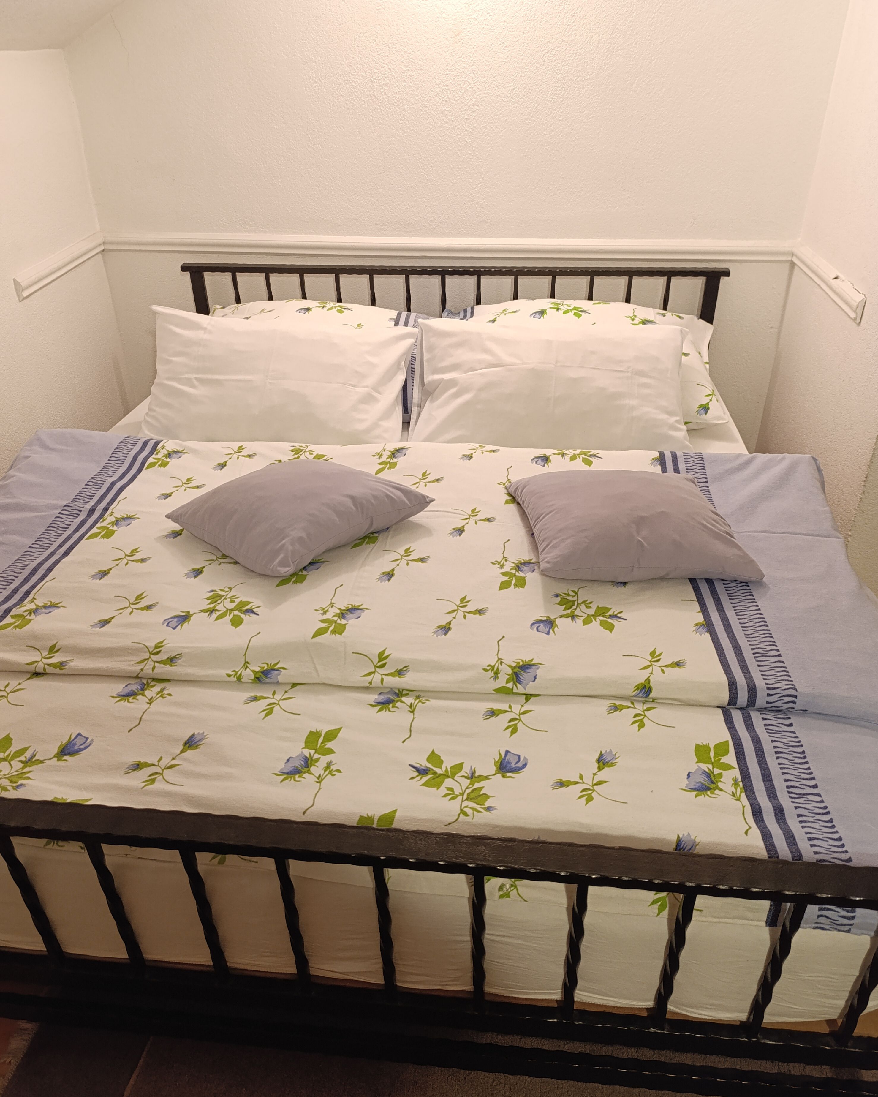 Una cama con una colcha estampada, dos almohadas y una funda de almohada a rayas.