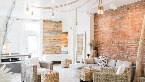 Ein gemütliches Wohnzimmer mit Rattanmöbeln, einer Ziegelwand und einer Wandverkleidung aus Holz.