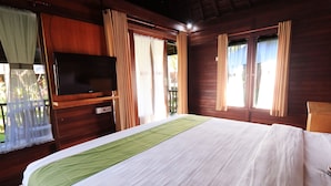 Un dormitorio con cama, cortinas, televisor y ventana.