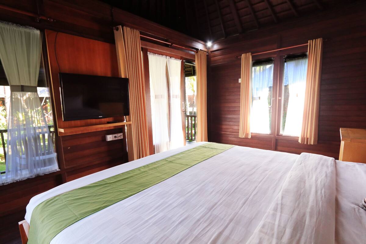 Een slaapkamer met een bed, gordijnen, een televisie en een raam.