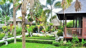 Un resort tropical con un pabellón de madera, exuberante follaje y construcciones tradicionales con techo de paja.