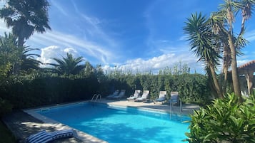 Una piscina al aire libre, sillones reclinables de piscina