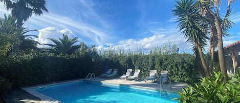 Una piscina al aire libre, sillones reclinables de piscina