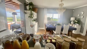 A dining area with a table set for a meal, surrounded by various food items and condiments. - Quinta dos Bravos (Ribeira Grande)