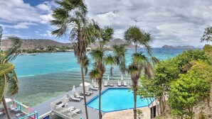 A pool area with lounge chairs and a view of the ocean. - Saint Thomas Condo w/ Ocean Views, Walk to Beach! (St. Thomas)