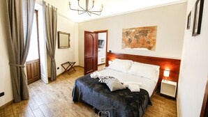 A hotel room with a large bed, a wooden headboard, a map on the wall, and a chandelier. - The Magnificent Apartment (Catania)