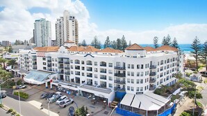 Un hotel a più piani con un cortile interno, circondato da alti edifici residenziali e vista sulla spiaggia.