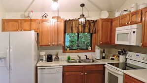 A kitchen with wooden cabinets, a refrigerator, a dishwasher, a microwave, and an oven.