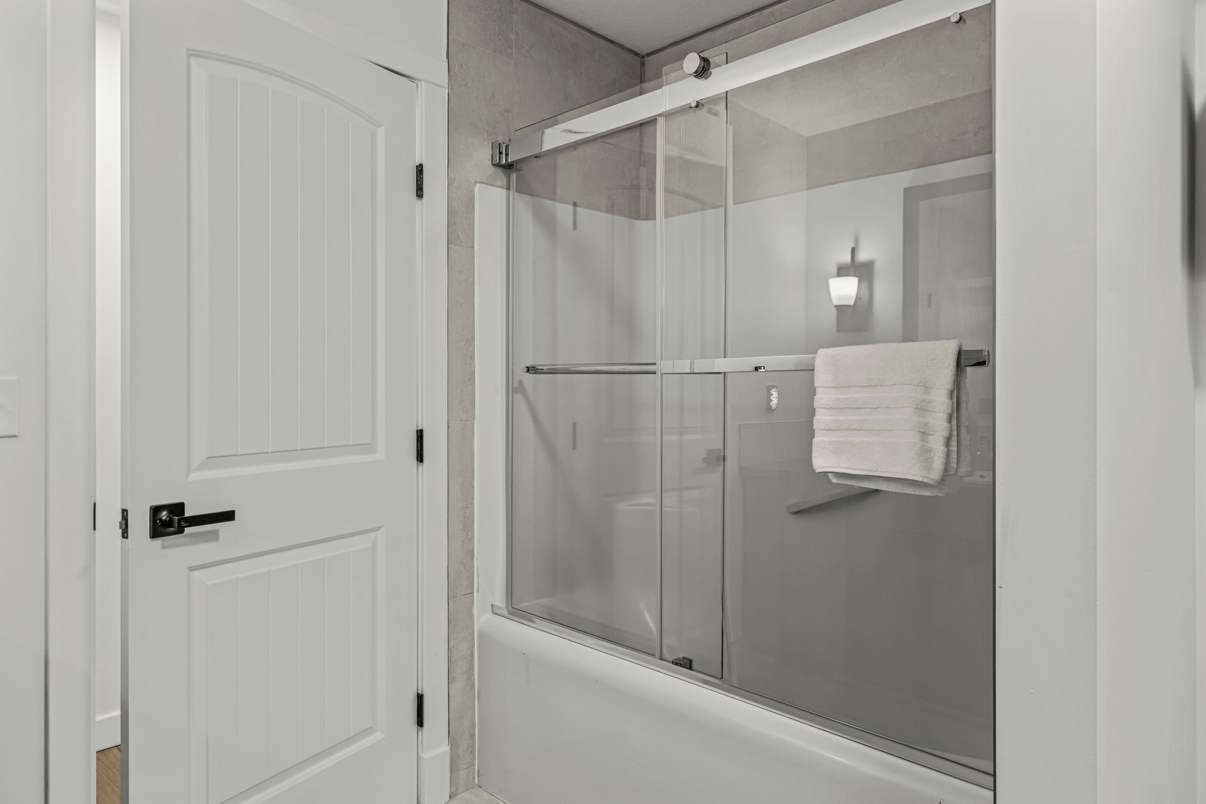 Une salle de bain avec une douche à parois de verre, une porte blanche et un porte-serviettes.