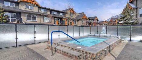 A residential area with a swimming pool, stone steps, and houses with wooden balconies.