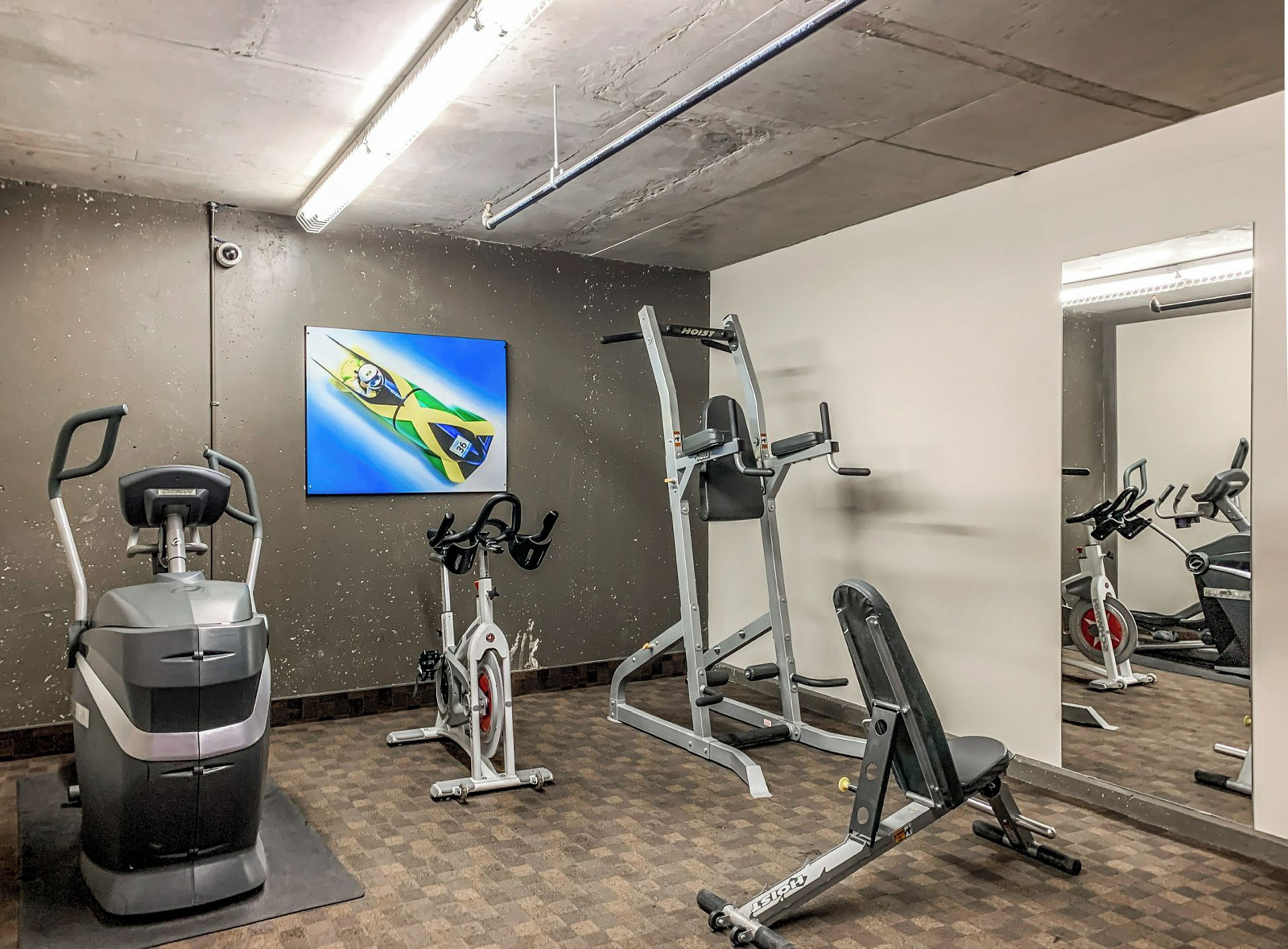 Un gimnasio con equipo de ejercicio, un espejo grande y un televisor montado en la pared.