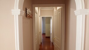 Un couloir aux portes blanches et au plancher en bois, qui mène à une pièce.