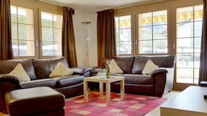 A living room with a brown leather sofa, a small wooden table, and a colorful rug.