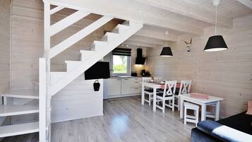 Eine moderne Küche mit weißen Schränken, ein Essbereich mit weißen Stühlen und eine Treppe mit weißen Geländern.