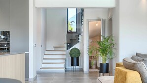A modern living room with a sofa, a dining area with a kitchen in the background, and a staircase leading to an upper floor. - Beautiful private villa for 8 guests with hot tub, private pool, WIFI, A/C, TV and terrace (Umag)