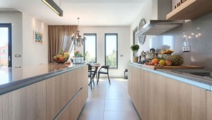 A modern kitchen with a central island, a dining area, and large windows. - Beautiful private villa for 8 guests with hot tub, private pool, WIFI, A/C, TV and terrace (Umag)