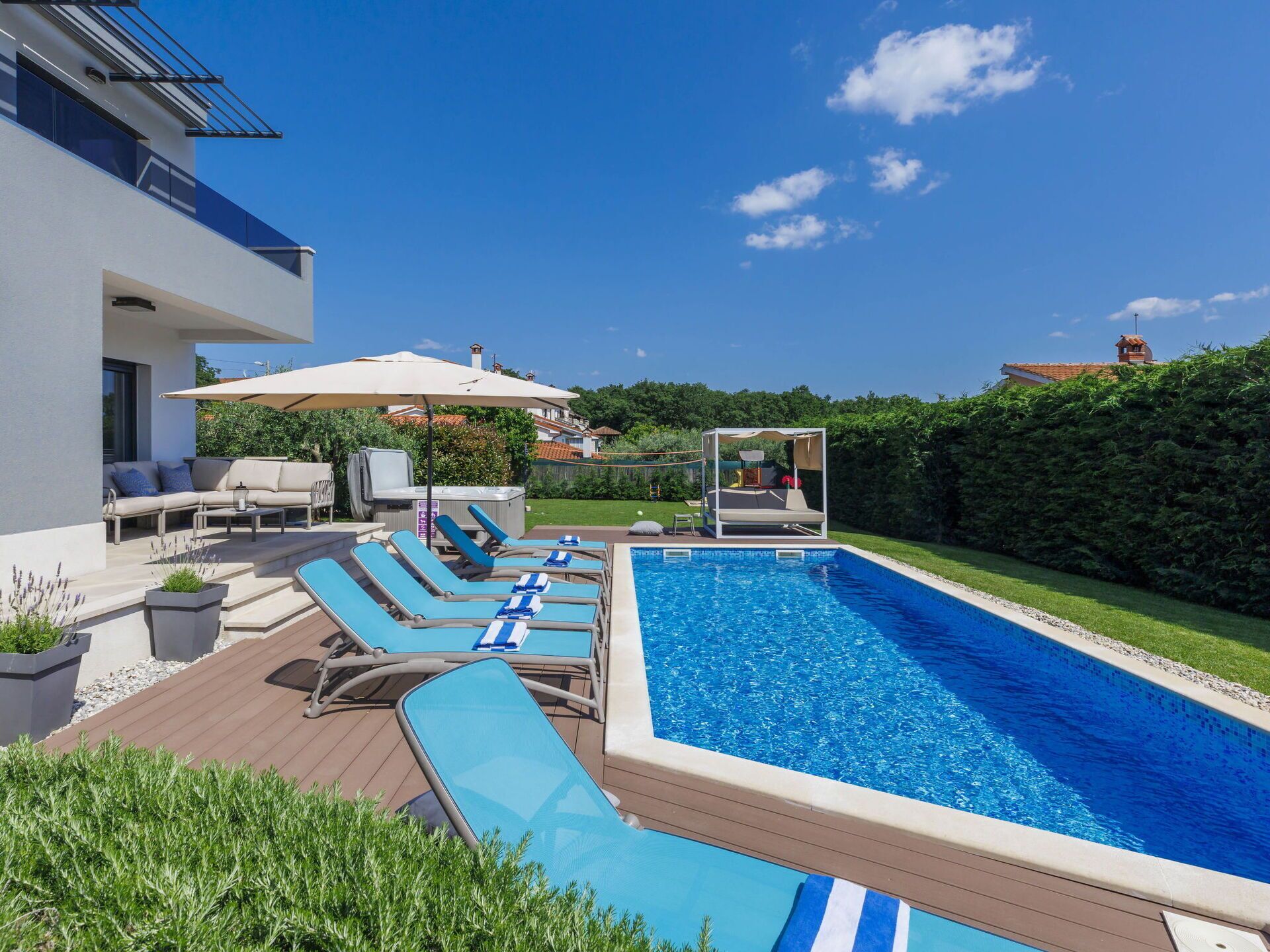 Un'area piscina moderna all'aperto con sdraio, vasca idromassaggio e un gazebo.