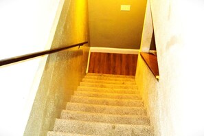 A staircase with carpeted steps leading to a wooden floor.