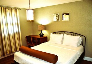 A hotel room with a bed, a nightstand, a lamp, and a window with curtains.
