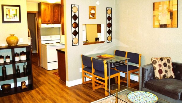 Un espacio habitable compacto con una mesa de comedor, dos sillas, un sofá y una cocina con armarios y estufa.