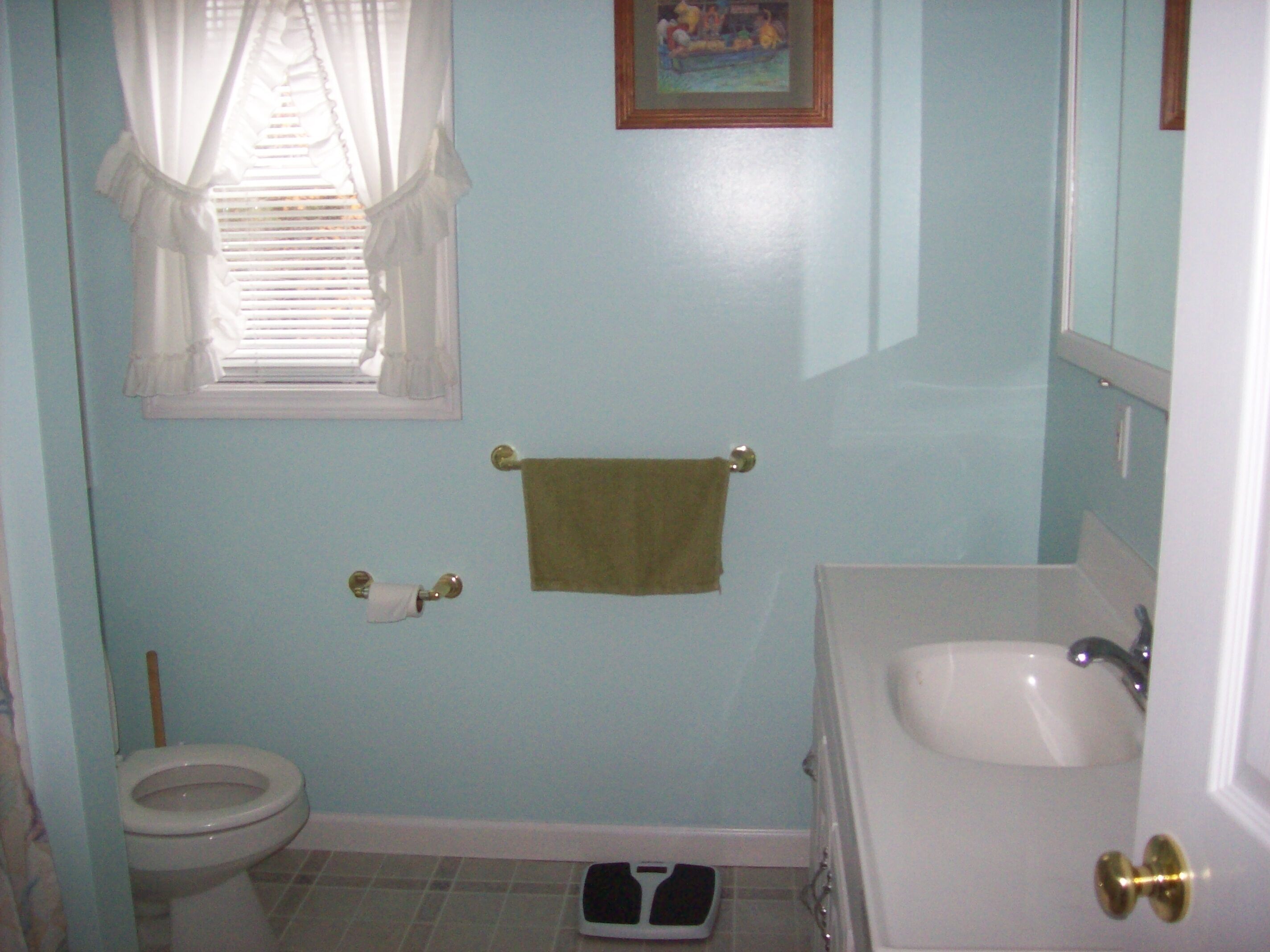 Une salle de bain avec des toilettes, un lavabo et une petite fenêtre avec des rideaux.