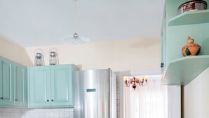 A kitchen with teal cabinets, a stainless steel refrigerator, a dining table with chairs, and a window with curtains. - Unique flat with Sea view by Athenian Home, Athenian Homes (Paleo Faliro)
