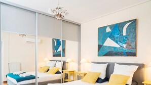 A modern hotel room with a large bed, a mirror, a blue abstract painting, and a chandelier. - Unique flat with Sea view by Athenian Home, Athenian Homes (Paleo Faliro)
