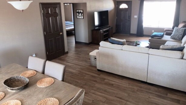 Una sala de estar con sofá, televisión y una mesa de comedor con individuales.