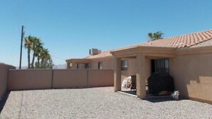 Un edificio residencial con techo de tejas, un patio cubierto y un camino de entrada de grava.
