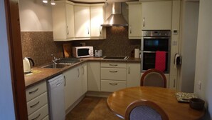 A compact kitchen with white cabinets, a microwave, a toaster, and a stainless steel oven.