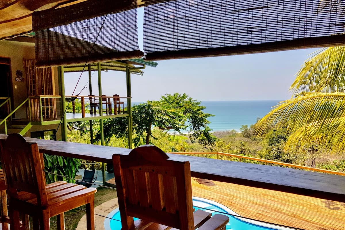 Eine Holzterrasse mit Pool mit Blick auf Strand und Meer.