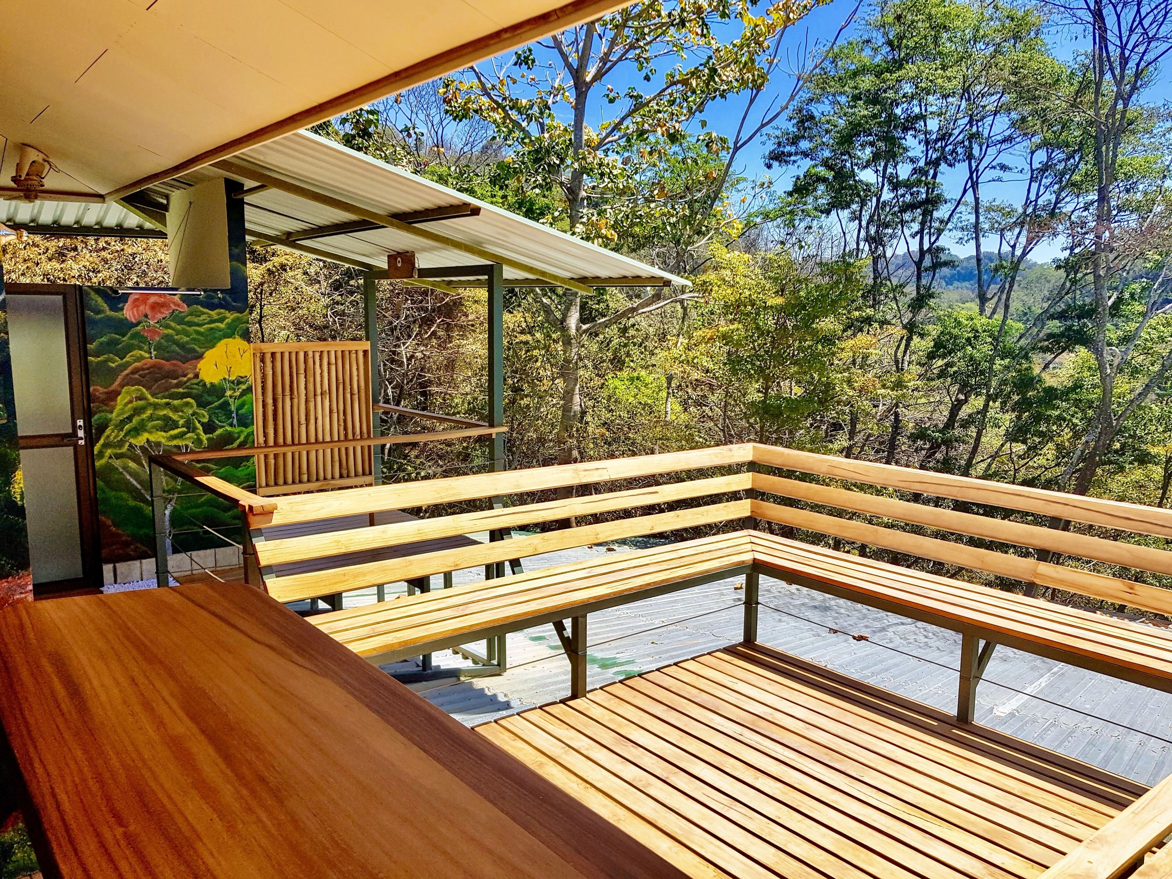 A wooden deck with benches overlooking a forested area.