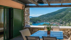 Un balcón con mesa y sillas, con vistas a un pueblo costero y montañas.