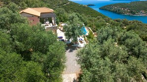Vista aérea de una villa con piscina, rodeada de abundante vegetación y con vistas a la costa.