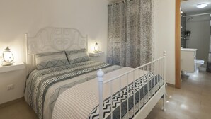 Ein Schlafzimmer mit einem Bett, Nachttischen und einem angrenzenden Badezimmer.