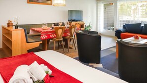 Una camera d'albergo con un letto, un tavolo da pranzo con sedie, una televisione e un divano.