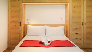 Un letto rifatto con lenzuola bianche, una coperta rossa e un bouquet di fiori bianchi e rossi.