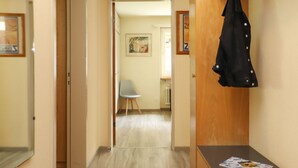 Un corridoio con una panca in legno, una sedia e un cappotto appeso al muro.