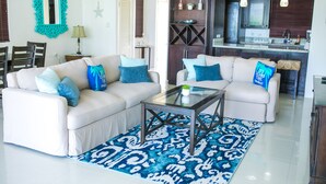 A living room with two white sofas, a glass coffee table, and a patterned rug. - Whispering Seas (Tower Isle)