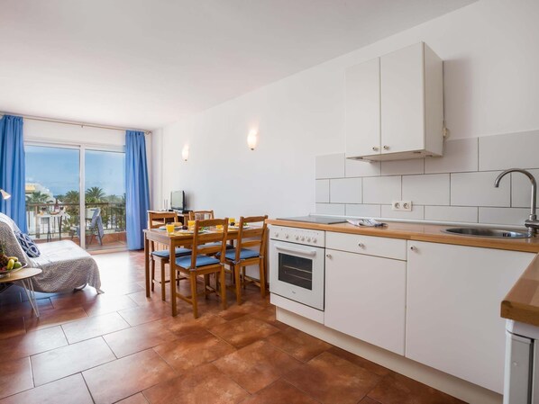 Une cuisine moderne avec des meubles blancs, un plan de travail en bois et un coin repas comprenant une table et des chaises.