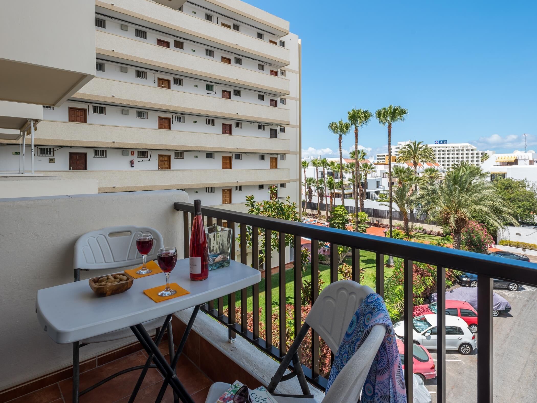 A balcony with a table set for two, a bottle of red wine, and a bowl of nuts.