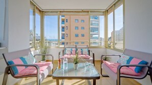 A bright room with a glass table, two sofas, and a view of a building through large windows. - Cosy apartment for 4 people with pool, A/C, WIFI, TV and terrace (Benissa)