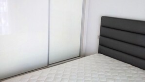 A bedroom with a bed, a wardrobe, and a white tiled floor.