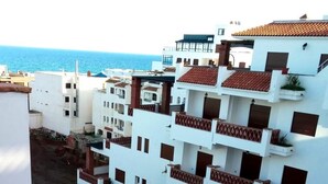 A coastal residential area with white buildings featuring red-tiled roofs and balconies.