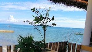 A patio with a white wicker sofa, a small white table, and a planter with green plants. - La Fourmi Hôtel (Nosy Be)