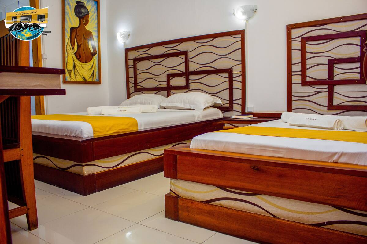 A hotel room with two wooden beds, white bedding, and a yellow accent.