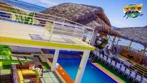 A pool area with a wooden deck, lounge chairs, and a view of the sea. - La Fourmi Hôtel (Nosy Be)