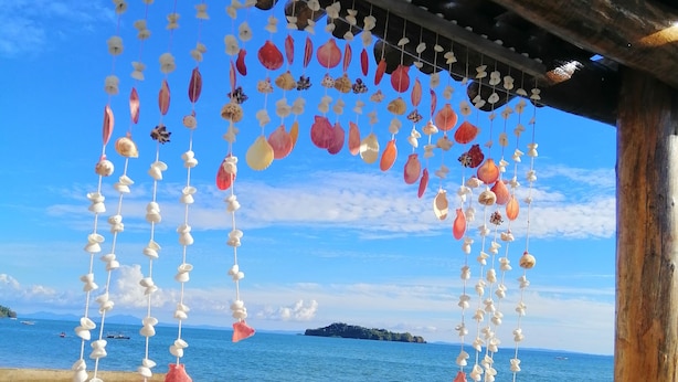 A beach scene with a wooden structure and hanging shells. - La Fourmi Hôtel (Nosy Be)
