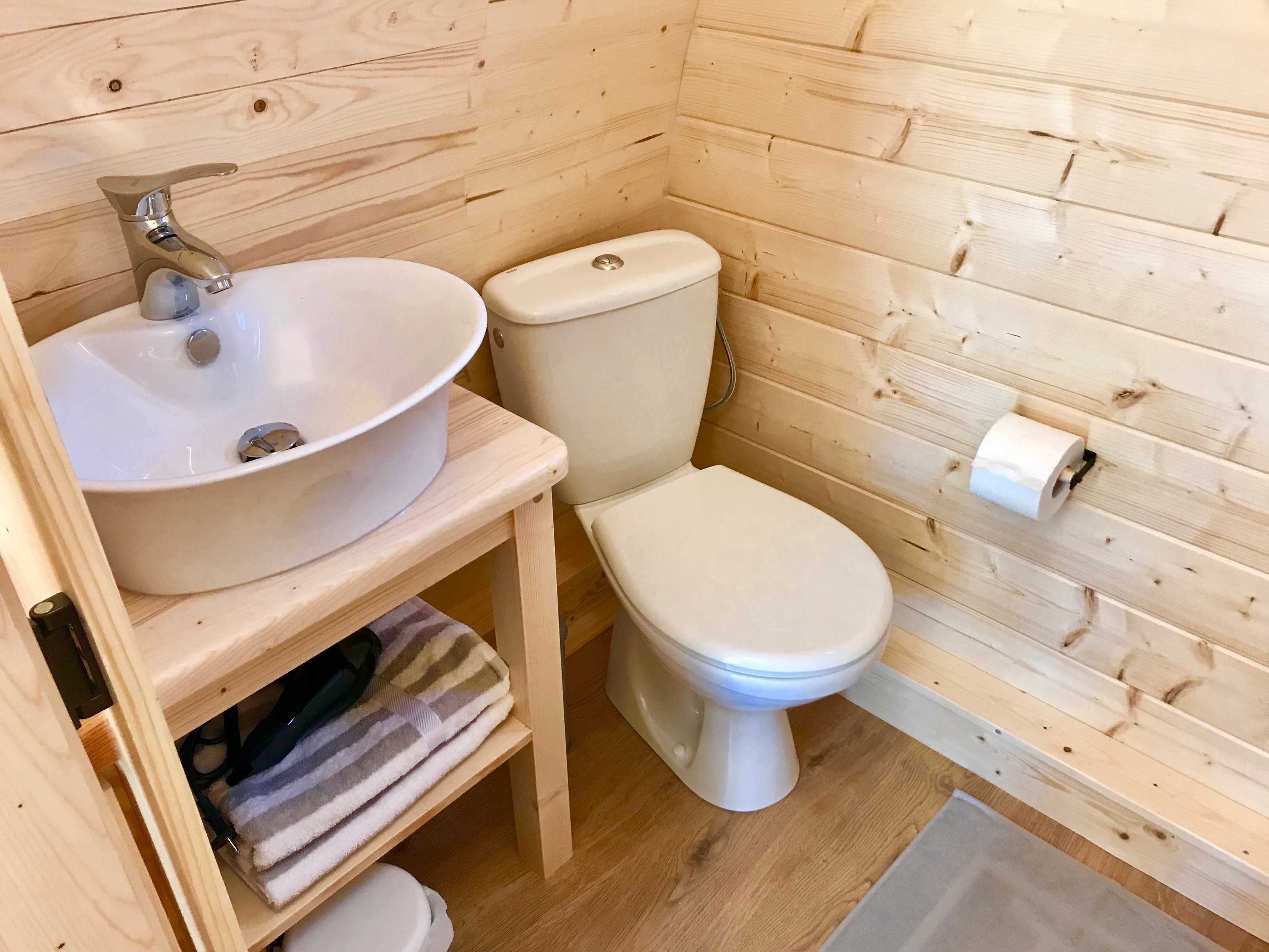 Ein Badezimmer einer Holzhütte mit Waschbecken, Toilette und Ablagefläche mit Handtüchern.